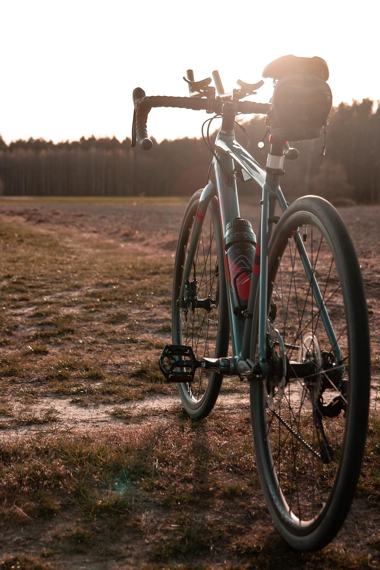 Gravelbike im Gegenlicht bei Sonnenuntergang auf einem Feldweg
